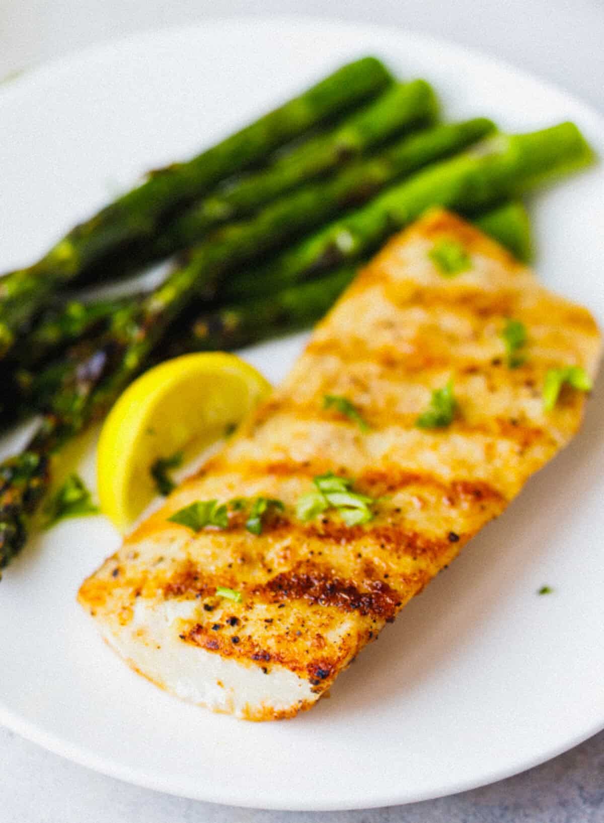 Close-up of grilled mahi mahi showing golden grill marks and smoky spice crust, topped with fresh herbs