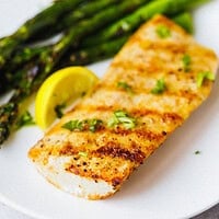 Close-up of grilled mahi mahi showing golden grill marks and smoky spice crust, topped with fresh herbs