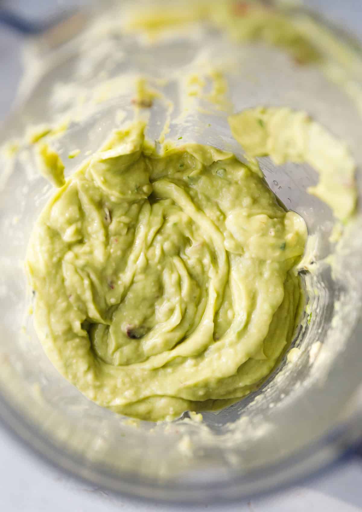 Freshly blended smooth guacamole inside a blender jar.