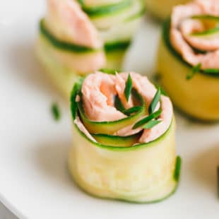 Smoked salmon and cucumber appetizer rolls on a white plate