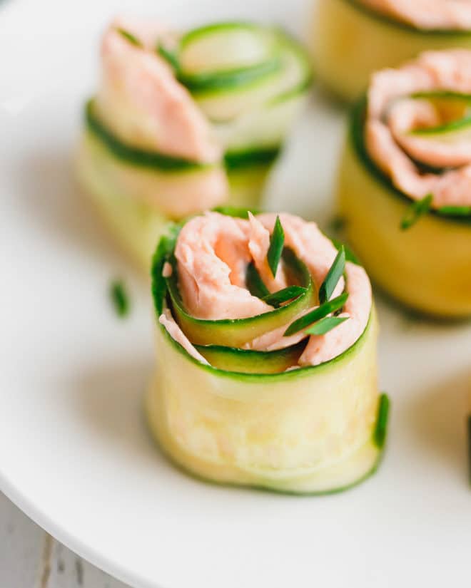 Smoked salmon and cucumber appetizer rolls on a white plate