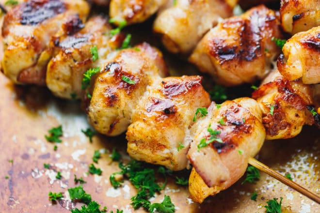 Bacon wrapped chicken kebabs on a baking dish