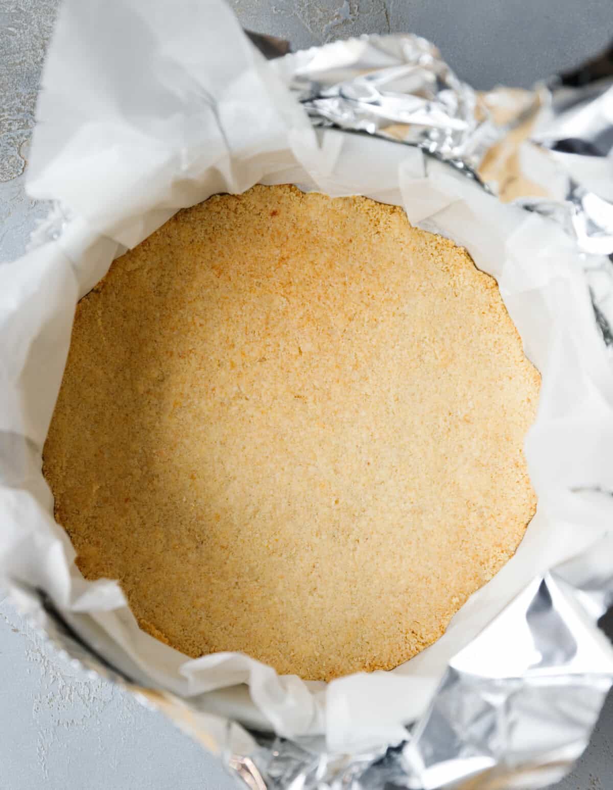 keto cheesecake almond flour crust pressed into springform pan lined with parchment paper