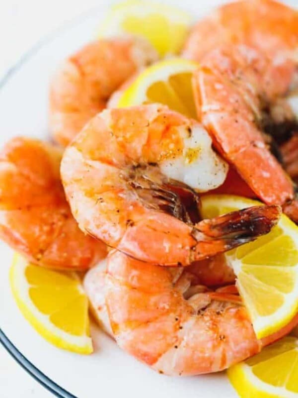 Broiled unpeeled shrimp on a white plate