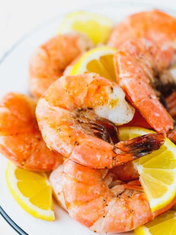 Broiled unpeeled shrimp on a white plate