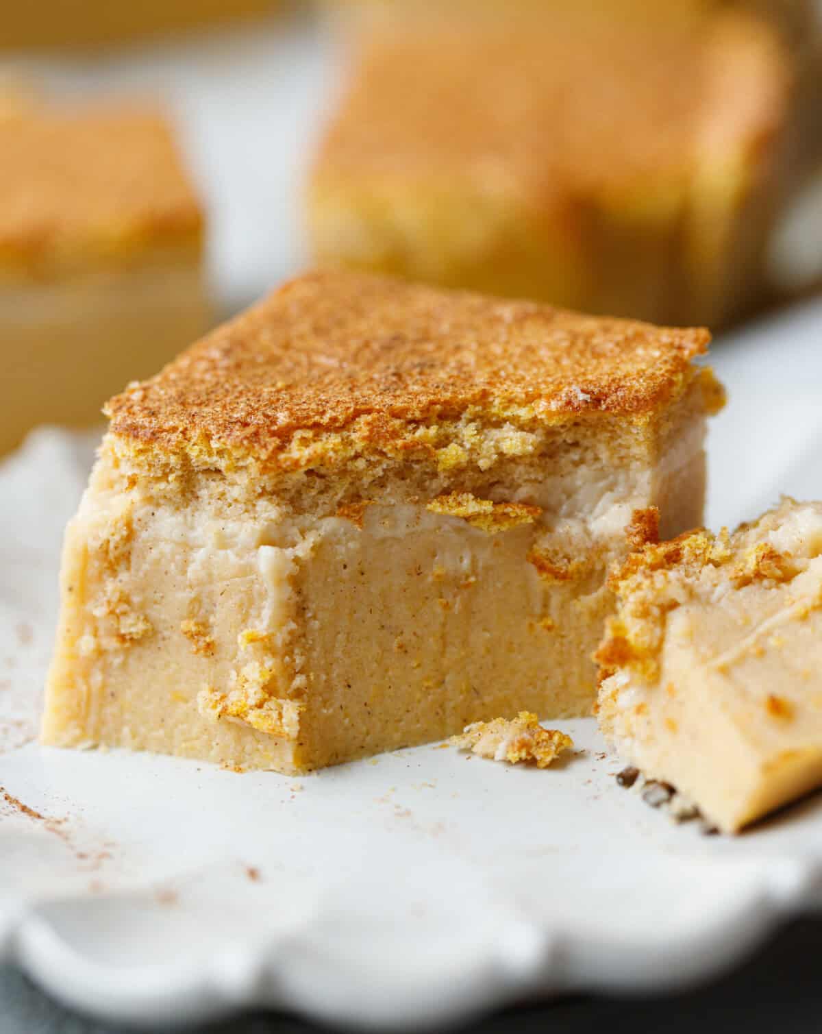 Close-up of pumpkin magic custard cake with a bite taken out, showing the silky pumpkin custard texture and fluffy top layer.