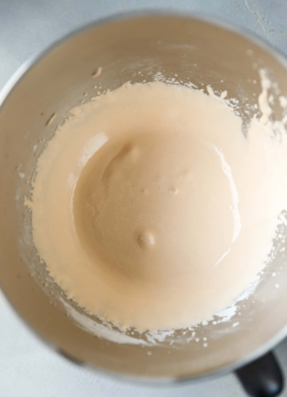 Whipped egg yolks and sugar mixture beaten until pale and frothy in a mixing bowl for pumpkin custard cake.
