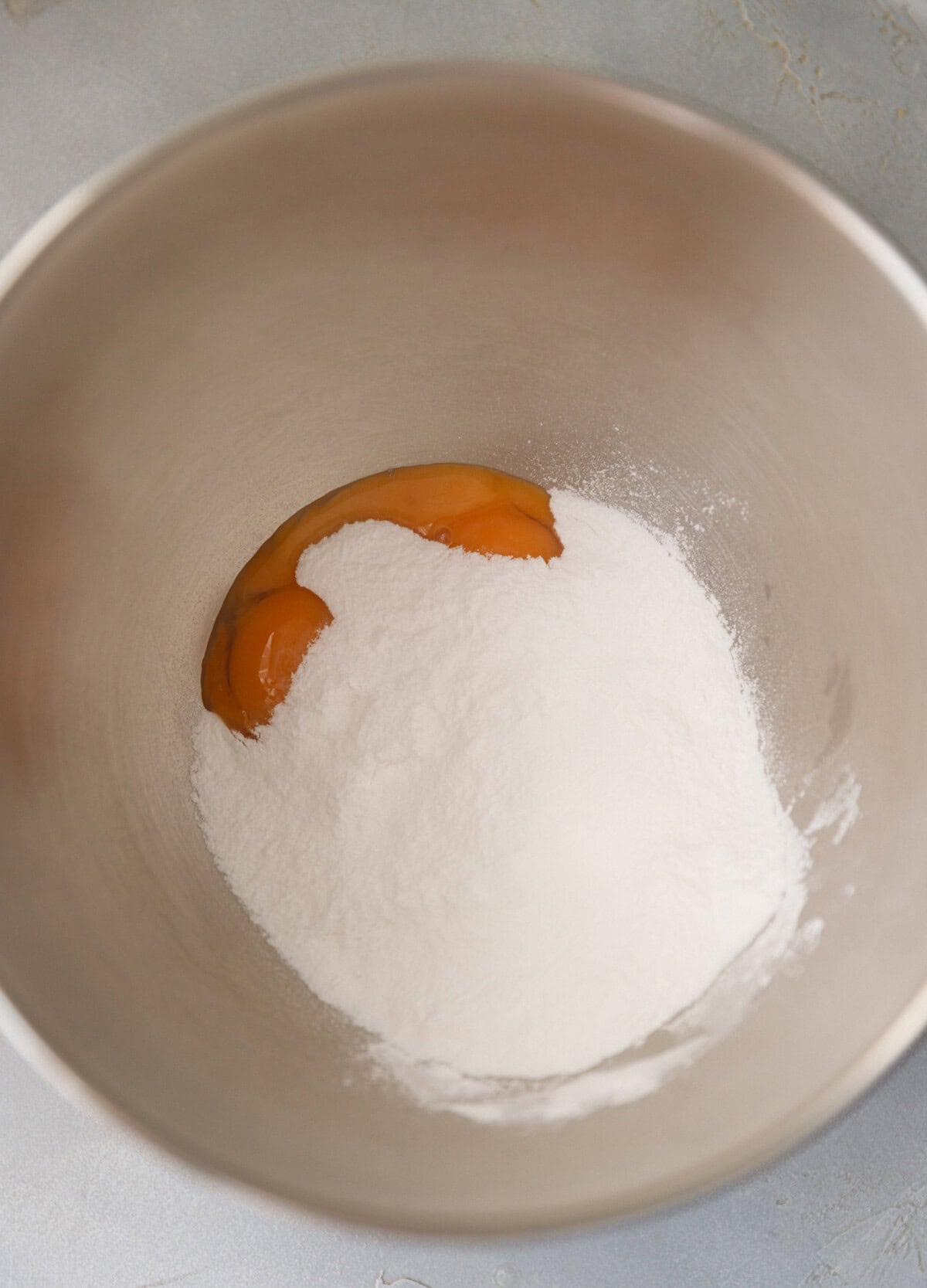 Egg yolks and powdered sugar in a mixing bowl before beating to make the pumpkin magic custard cake batter.