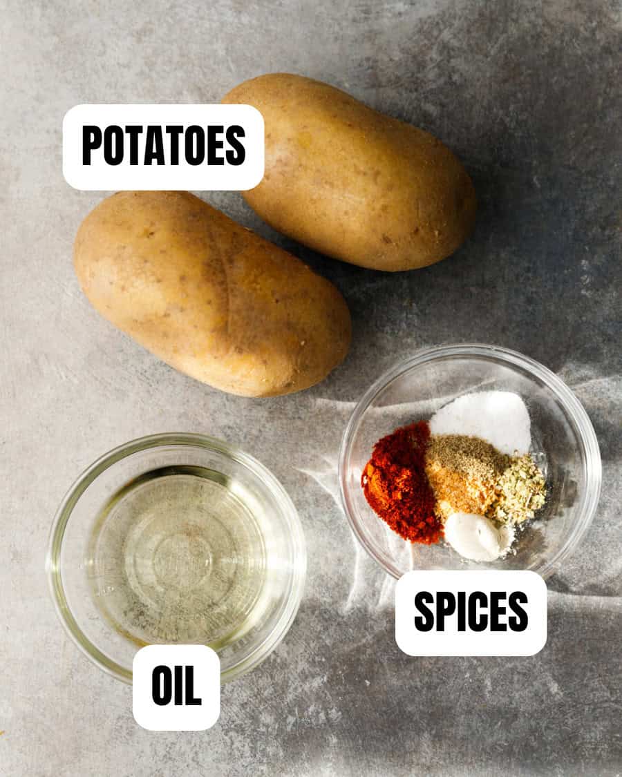 Potatoes, oil and spices displayed on a countertop for homemade oven fries.