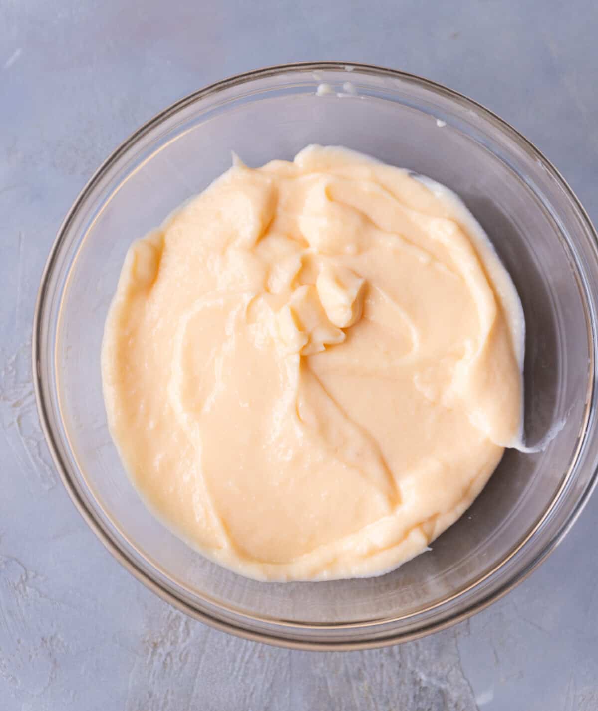 A glass bowl with homemade custard ready to be covered with plastic wrap.
