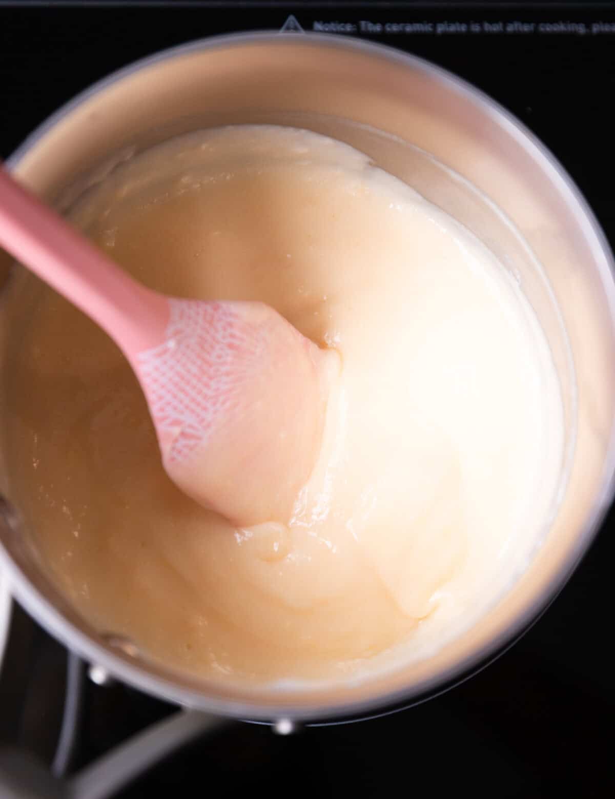 Cooked, thickened vanilla custard in a saucepan on an stove top.
