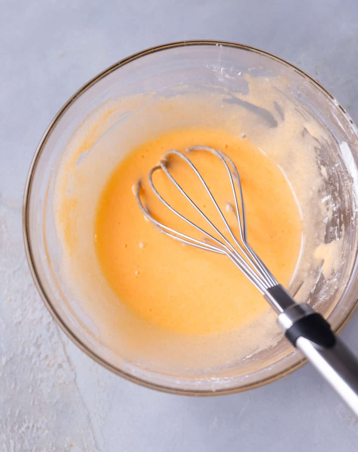 A glass bowl with mixed egg yolks, sugar and cornstarch.