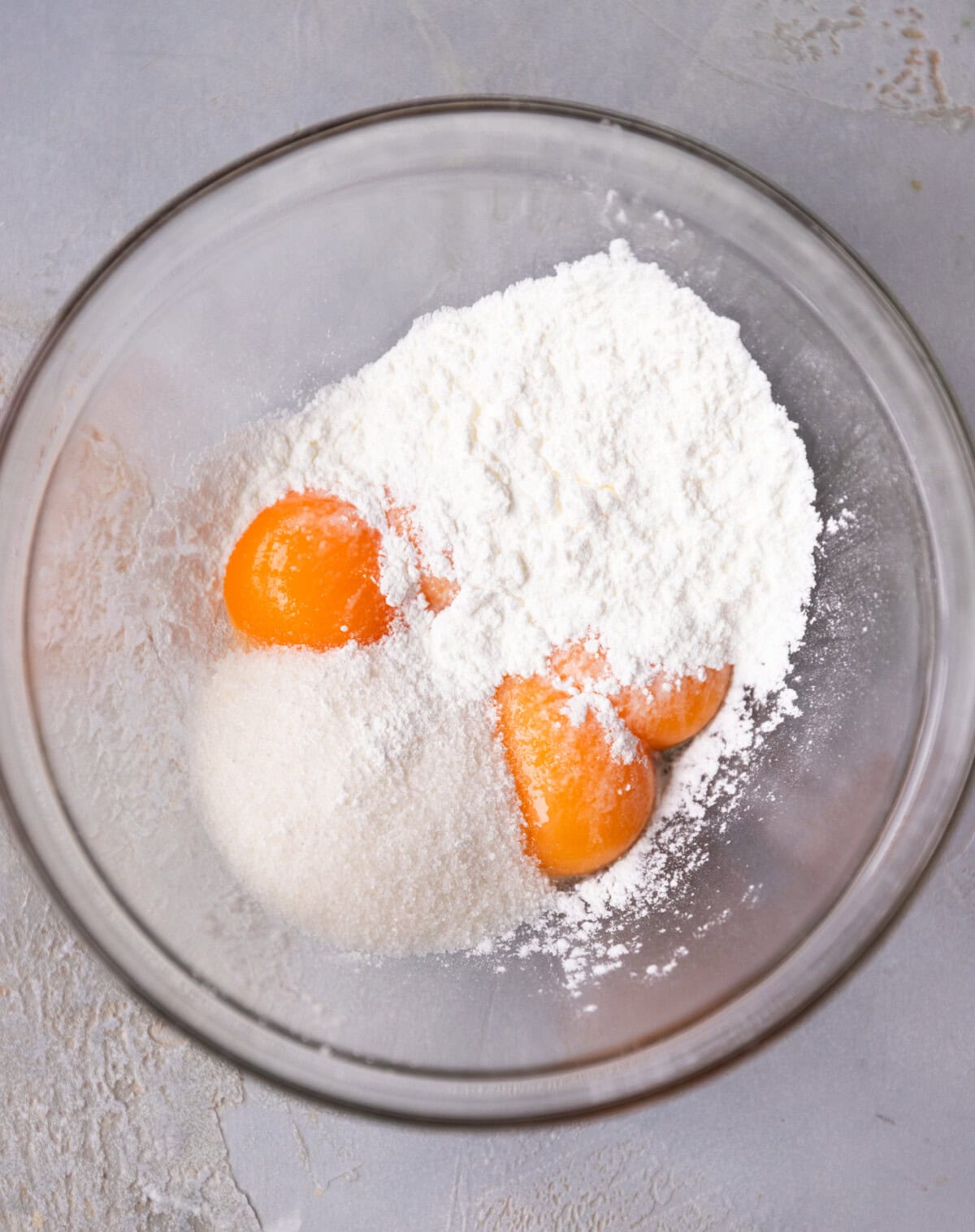 A glass bowl with egg yolks, sugar and cornstarch