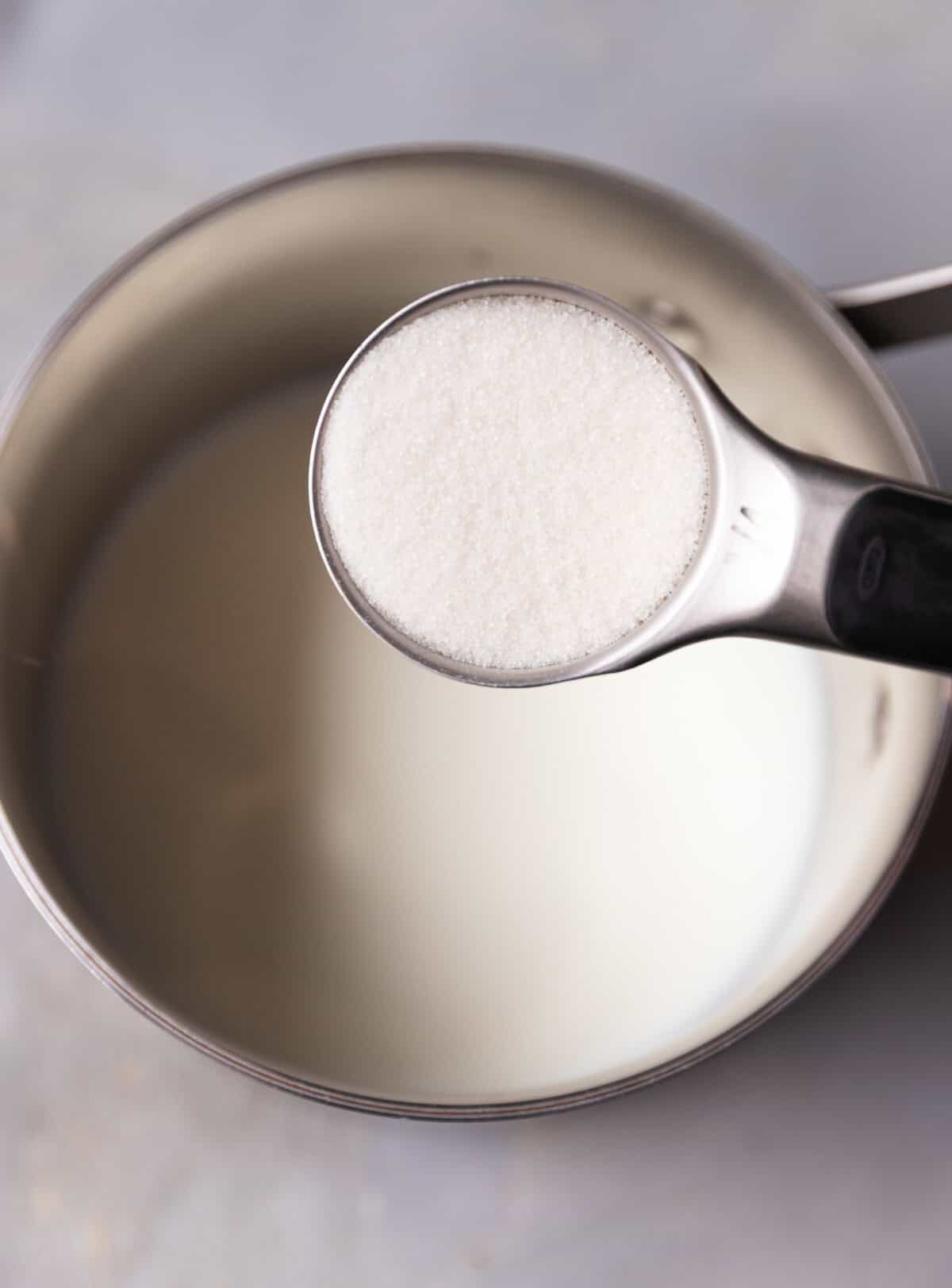 A saucepan with milk and sugar added to it.