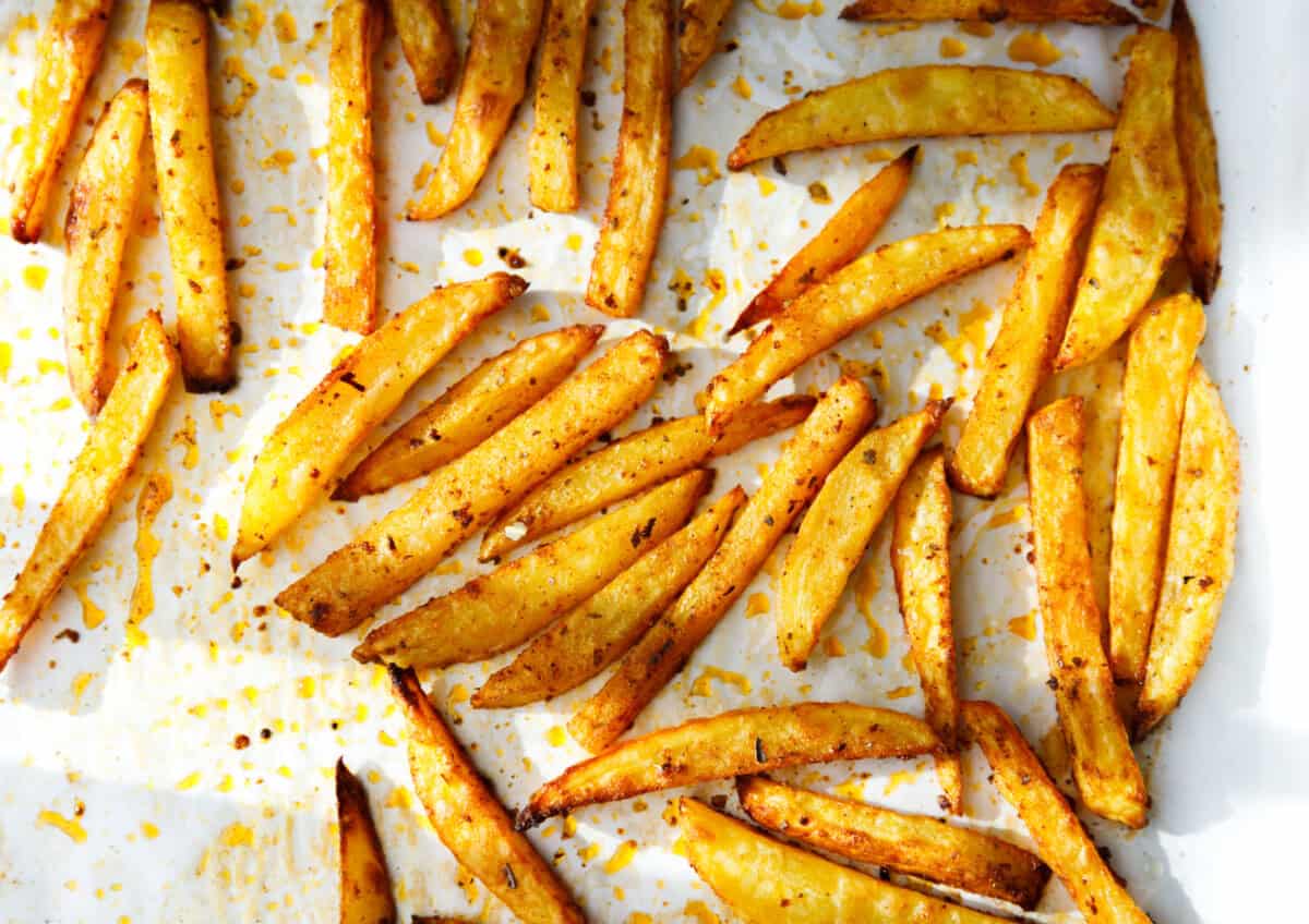 Crispy baked oven fries on parchment paper after roasting.