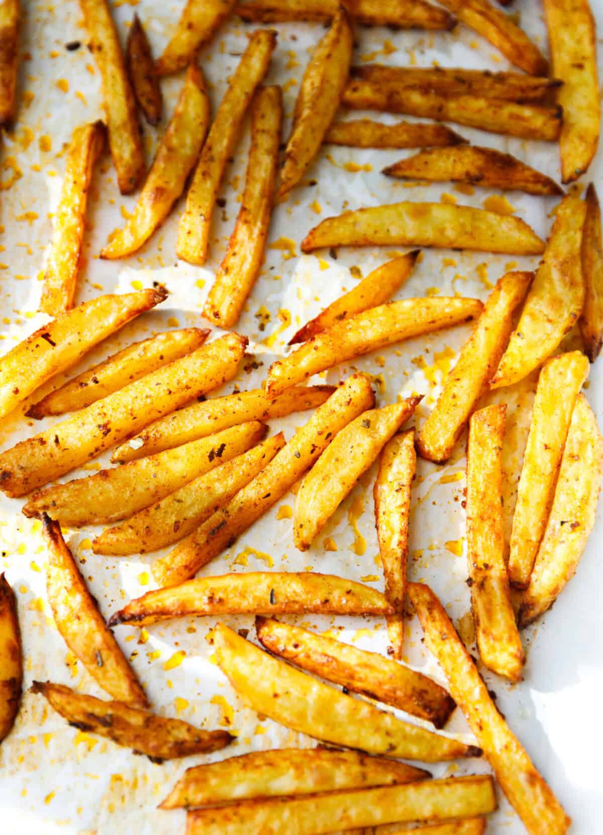 Golden brown baked oven fries on parchment paper.