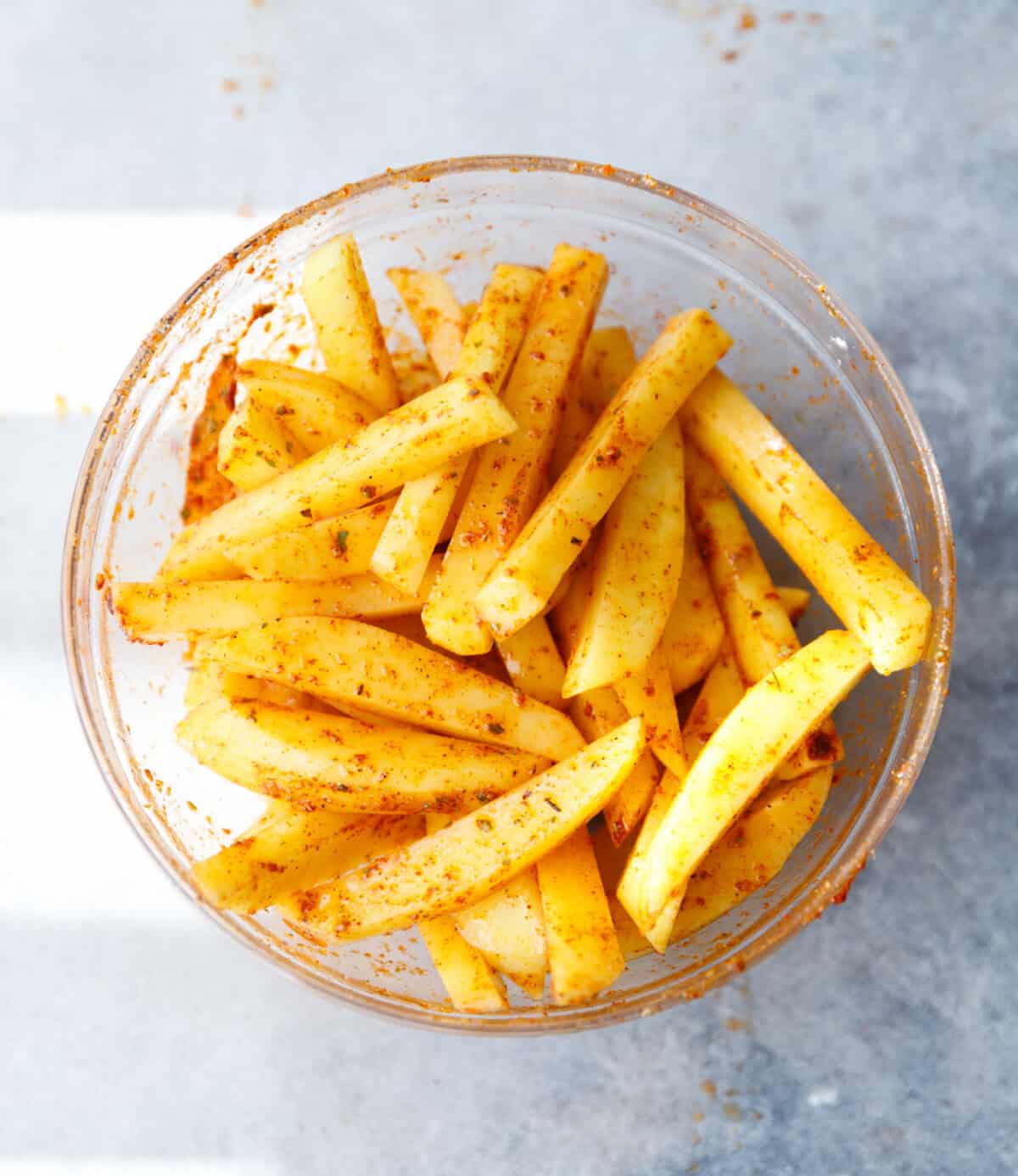 Seasoned potato matchsticks evenly coated and ready for baking.