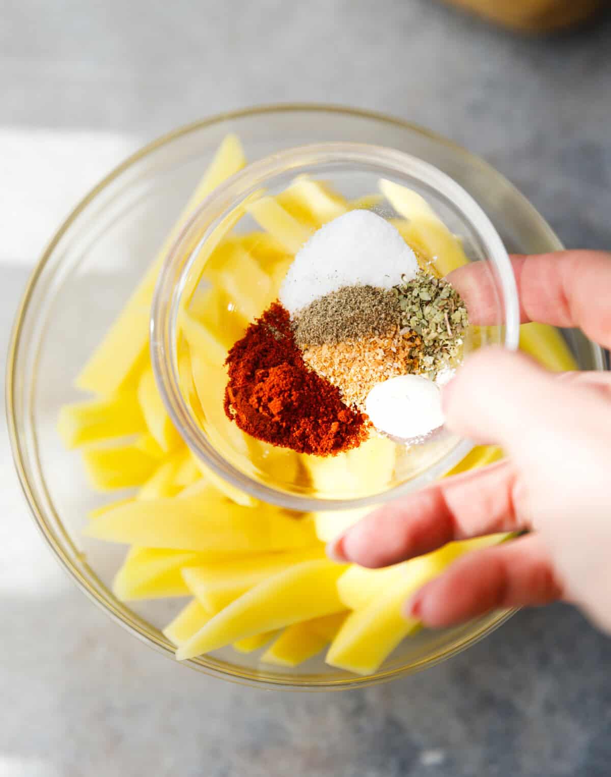 Russet potatoes and seasonings arranged on a countertop for oven fries.