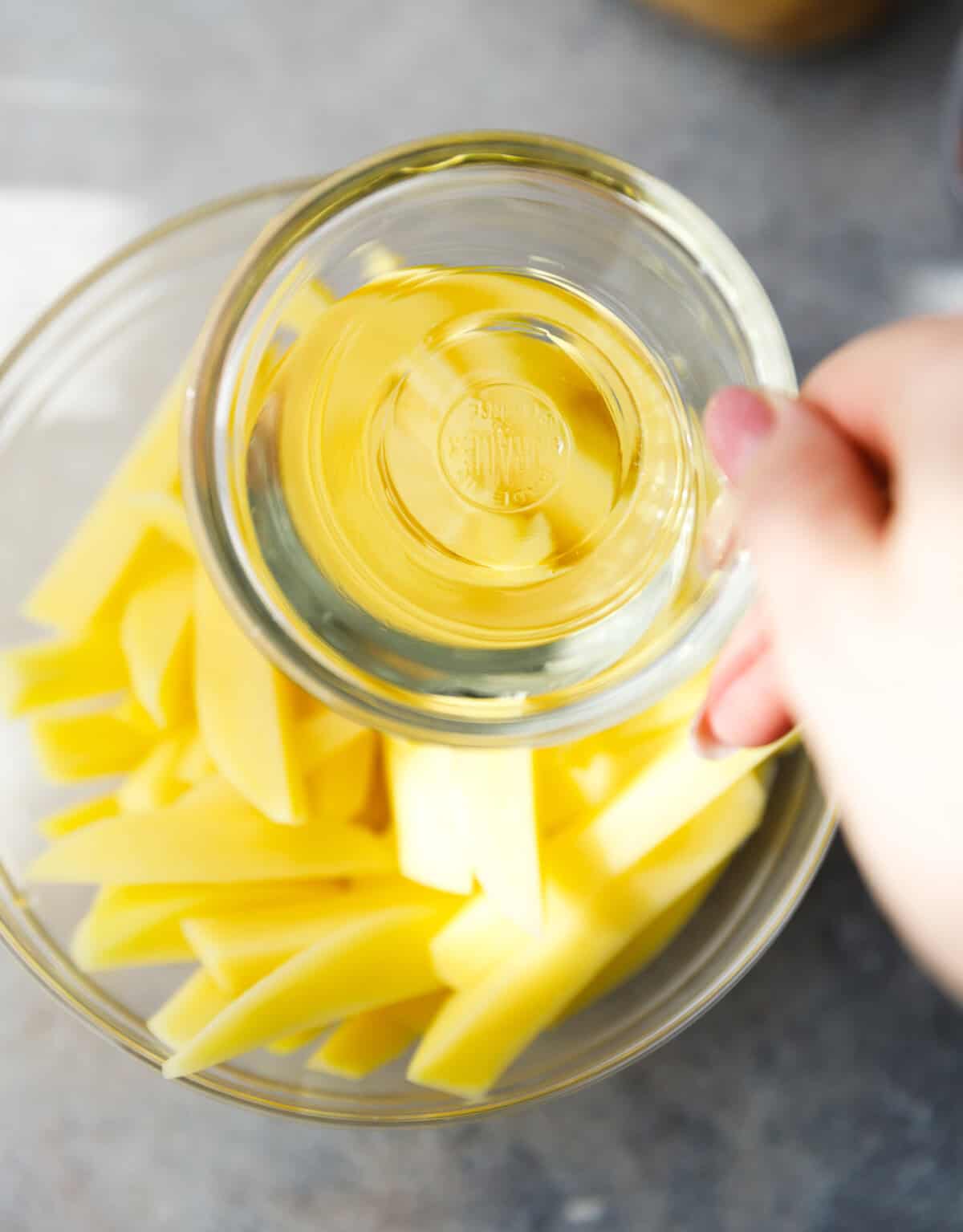 Russet potatoes with oil in a bowl.