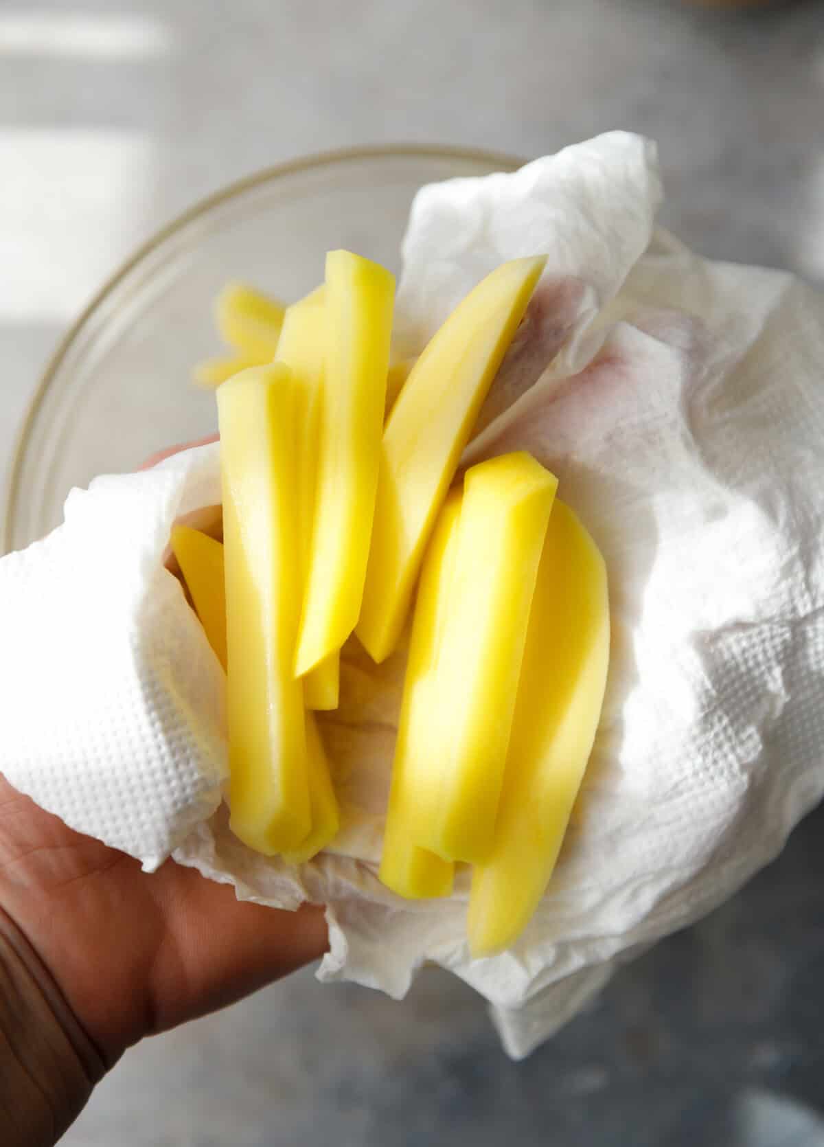 Russet potatoes, oil and seasonings arranged on a countertop for oven fries.