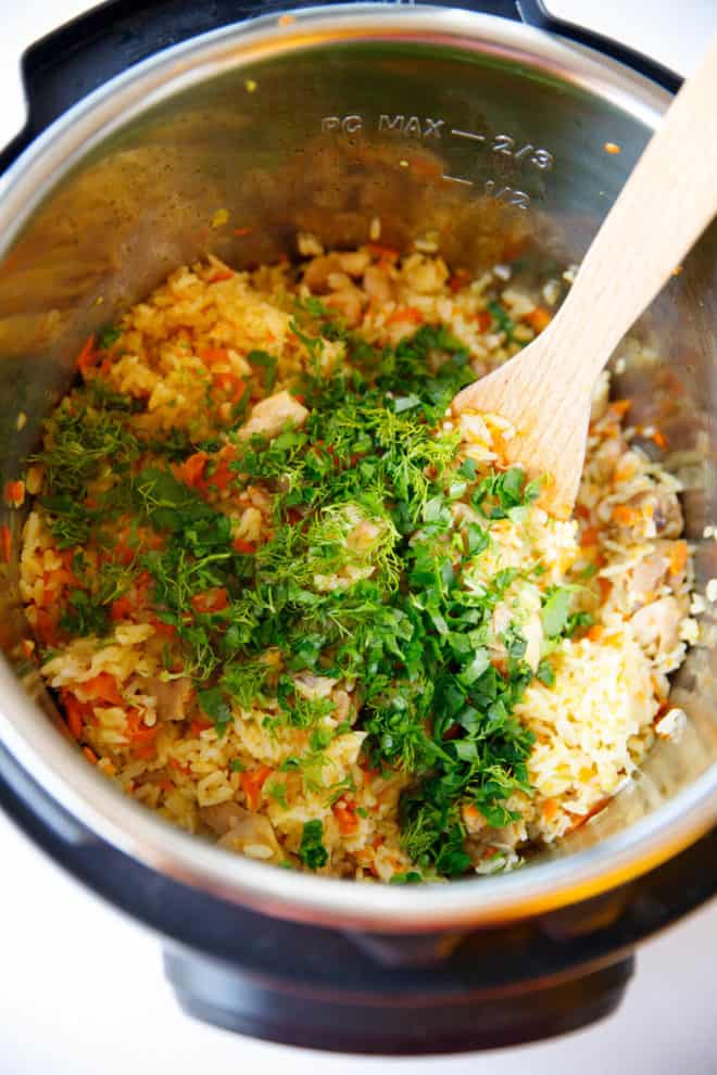 Chicken and rice in an instant pot topped with parsley and dill