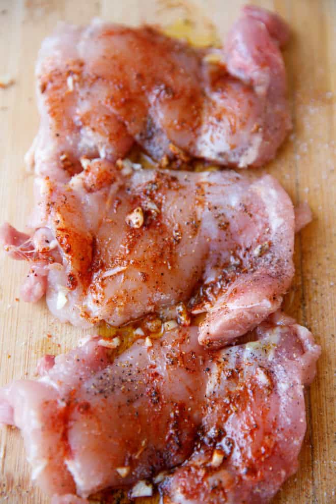 Raw boneless skinless chicken thighs on a cutting board