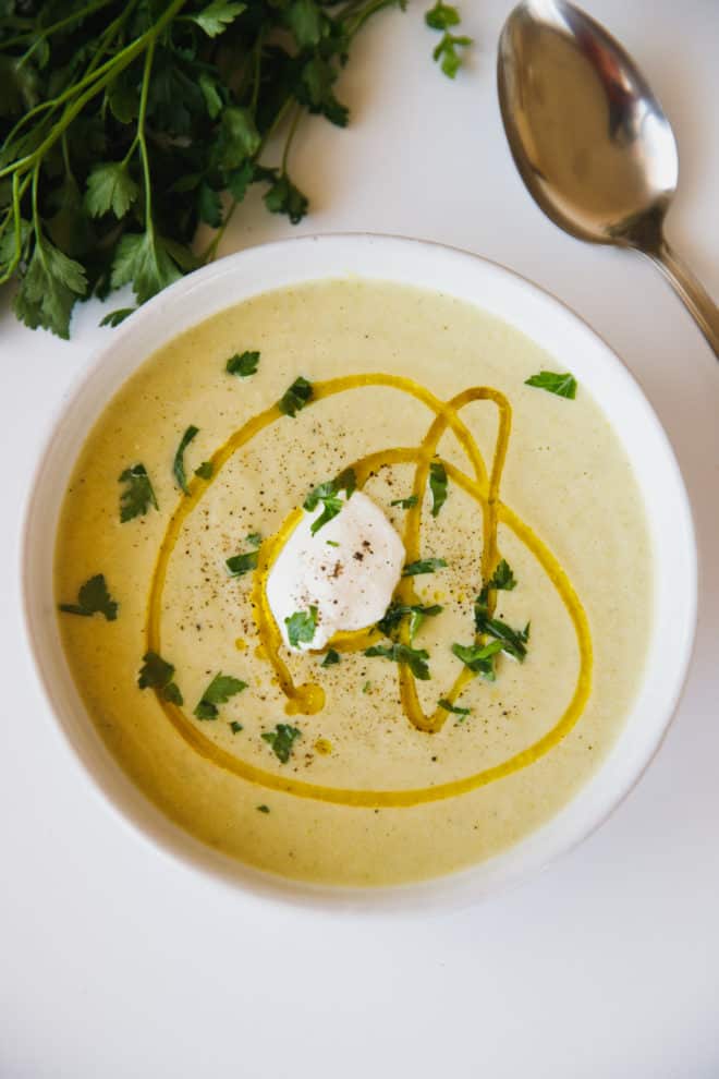 Zucchini soup in a bowl topped with sour cream
