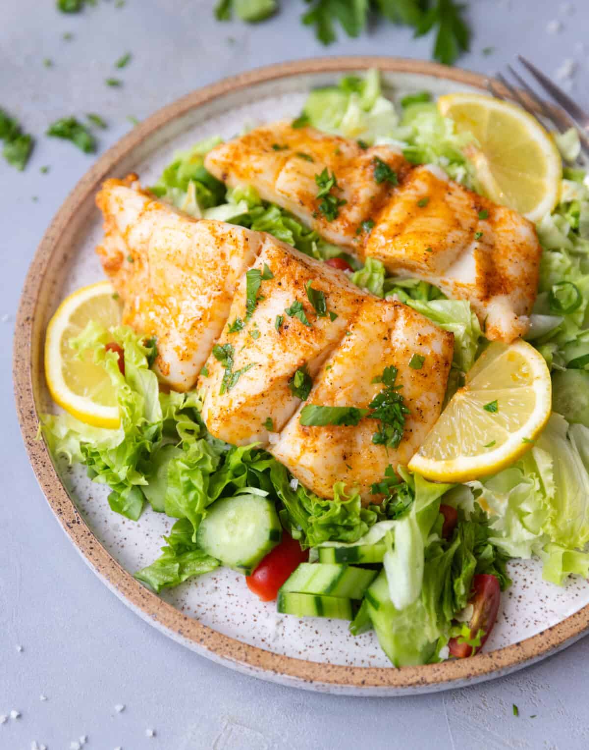 Juicy oven baked halibut fillets plated with mixed greens and herbs