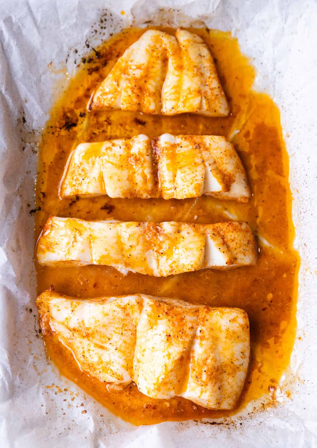 Oven-baked halibut fillets hot from the oven in a white dish