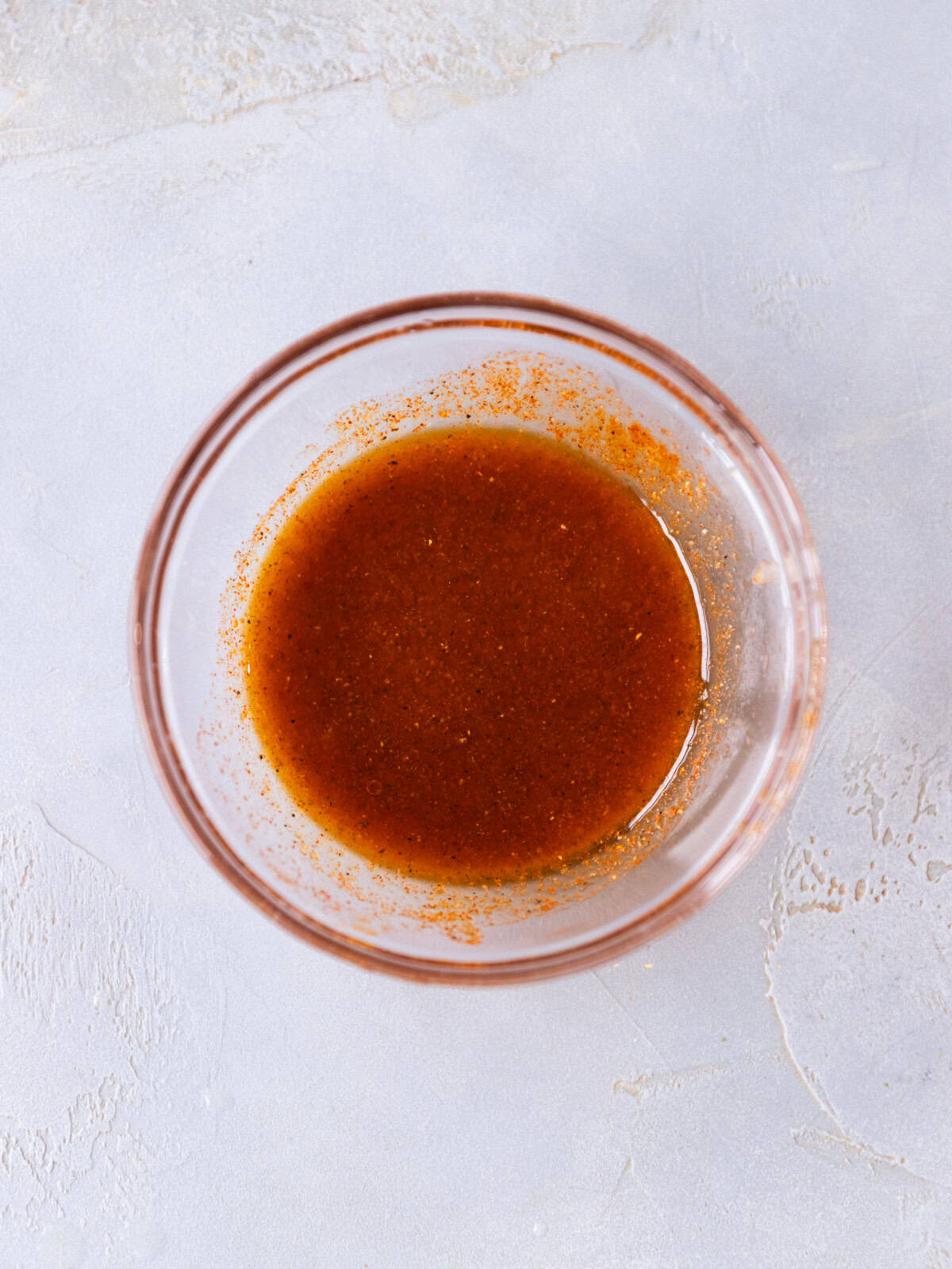 A glass bowl with olive oil, salt, pepper, paprika, garlic and lemon juice for Halibut fish.