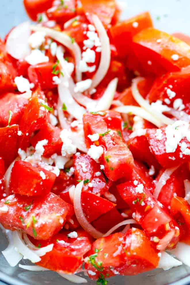 cut tomatoes with feta and onion in a bowl