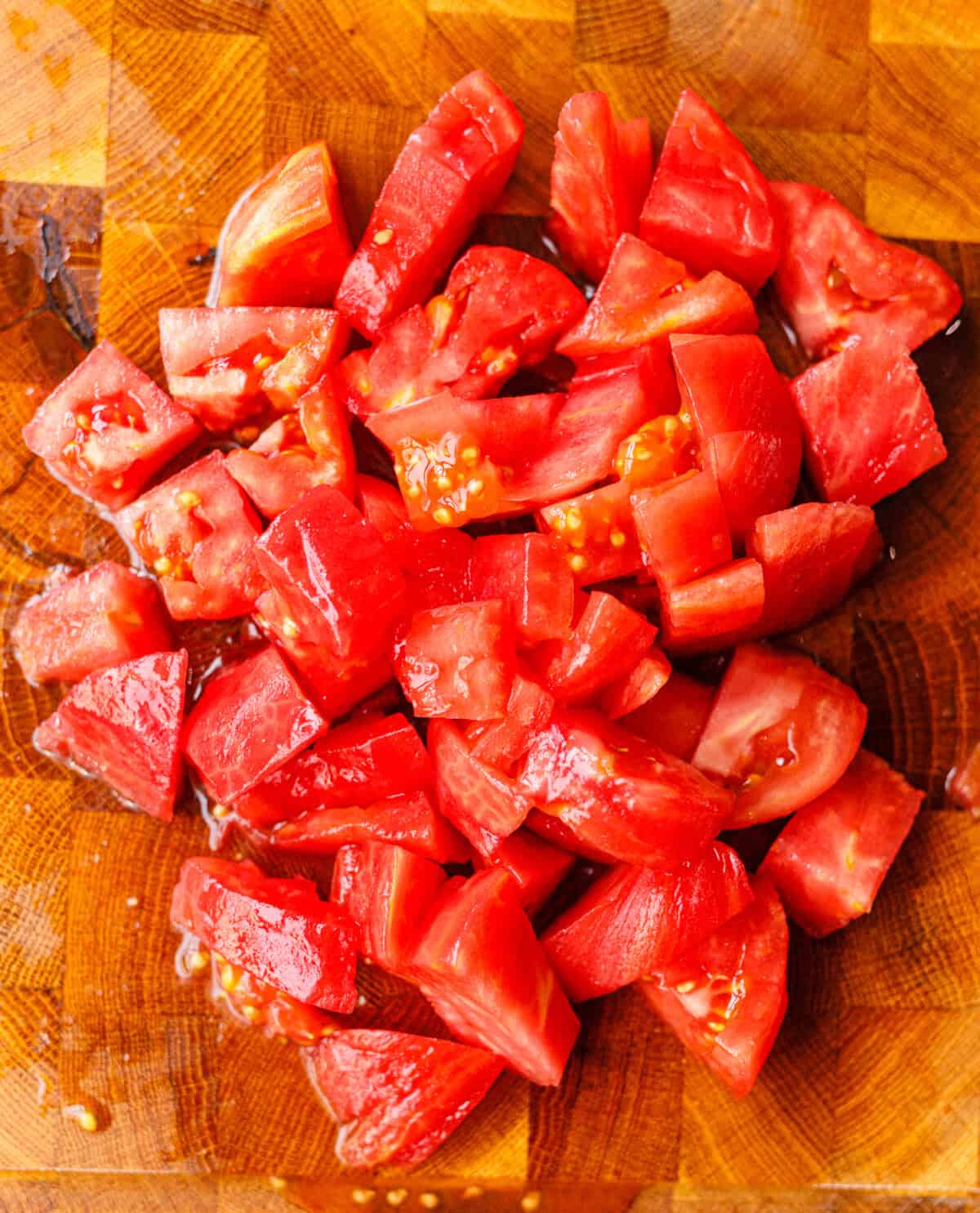 Ripe tomatoes cut into bite-sized chunks on a wooden board for tomato salad