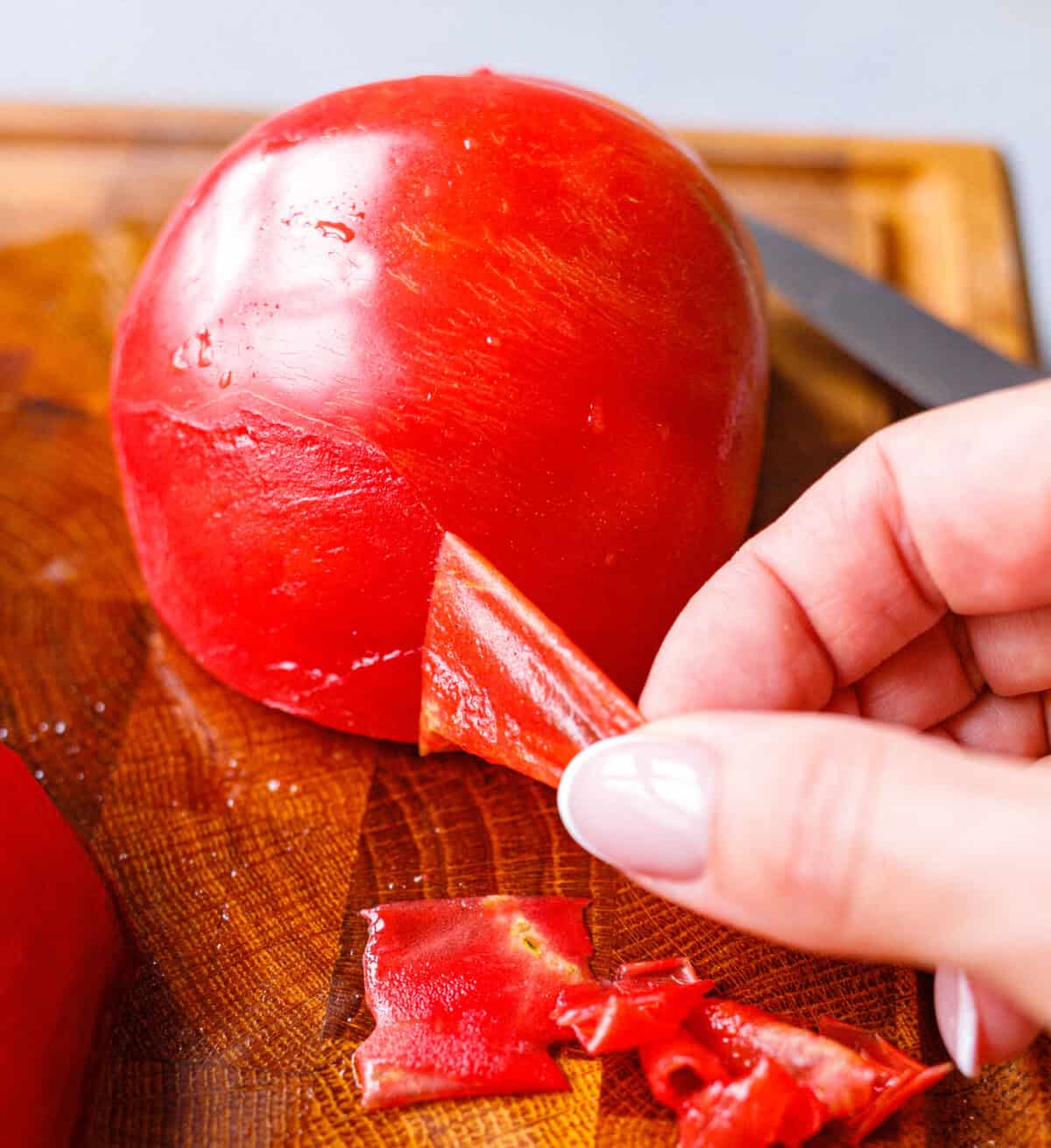 Peeling the skin off a blanched tomato by hand for Bulgarian tomato salad