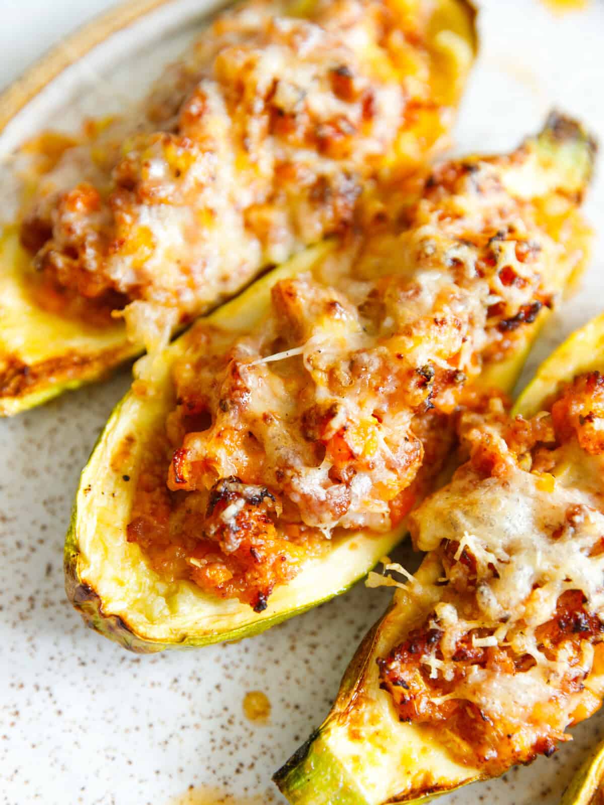 Close-up of stuffed zucchini boats with bubbly melted mozzarella and Parmesan over ground beef filling