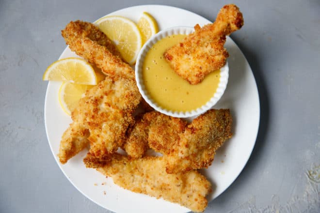 Ari fryer chicken strips on a plate with honey mustard dipping sauce