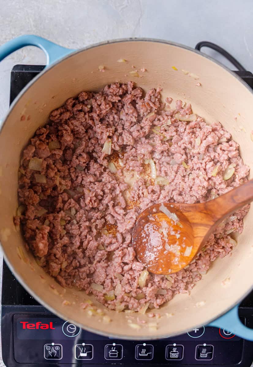 Browned ground beef and onions in a Dutch oven, ready for seasonings and tomatoes — the flavorful first step in making hearty low-carb Keto Cabbage Roll Soup.