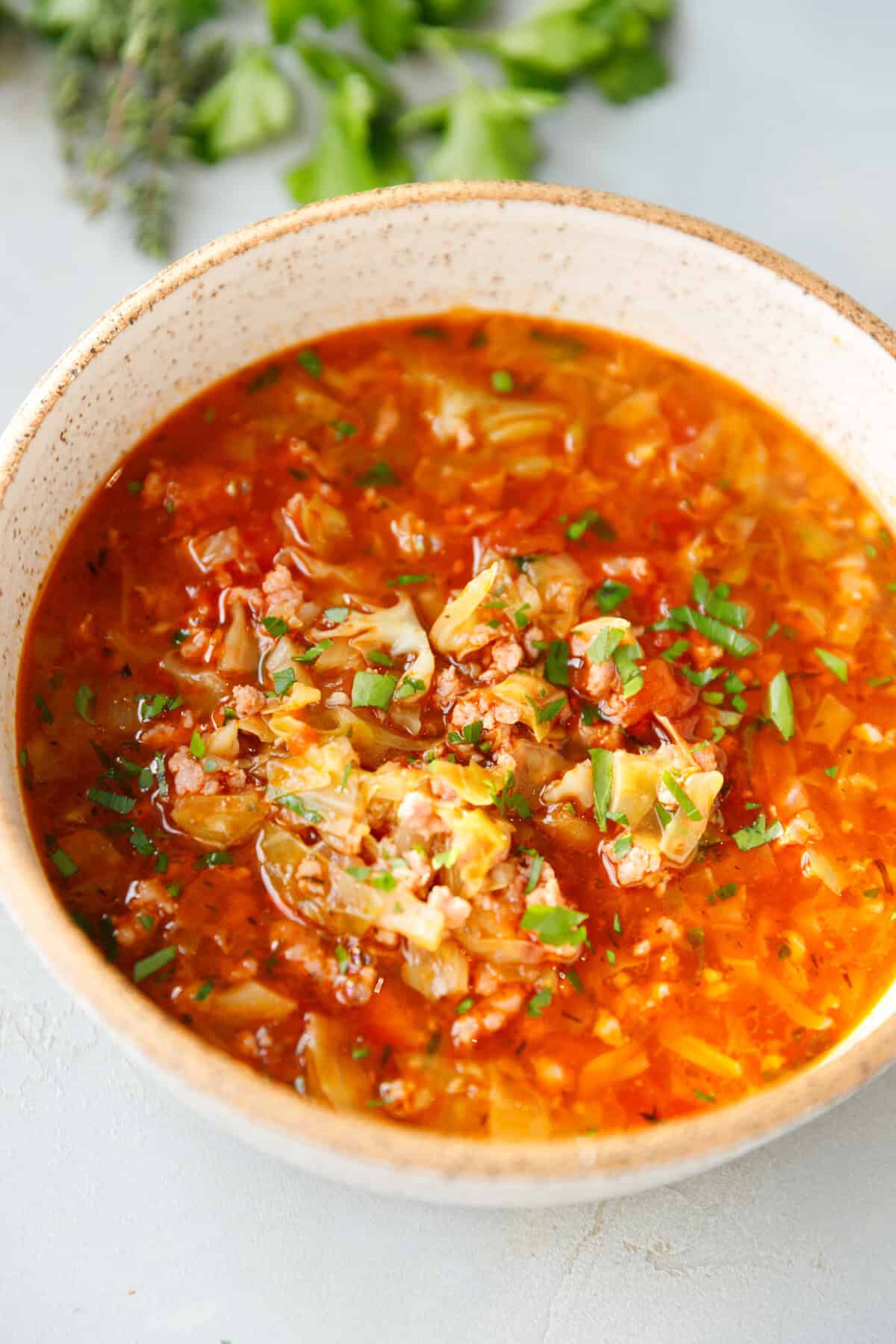 Warm bowl of Keto Cabbage Roll Soup with cabbage, beef, and tomatoes in a rich red broth, topped with fresh parsley - healthy, low-carb comfort food for busy nights.
