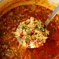 Ladle of Keto Cabbage Roll Soup in a Dutch oven filled with tender cabbage, ground beef, and tomatoes in a rich, flavorful broth - hearty low-carb soup perfect for meal prep.