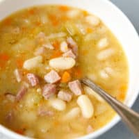 A white bowl with ham and bean soup