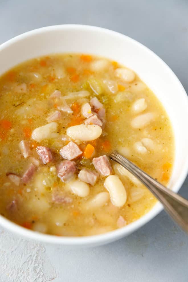 A white bowl with ham and bean soup
