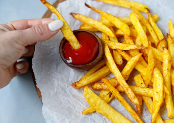 Air fryer fries on paper with bowl of ketchup for sipping