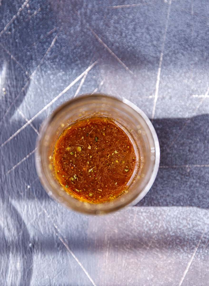 Balsamic vinaigrette dressing mixed in a glass jar on a sunlit countertop.