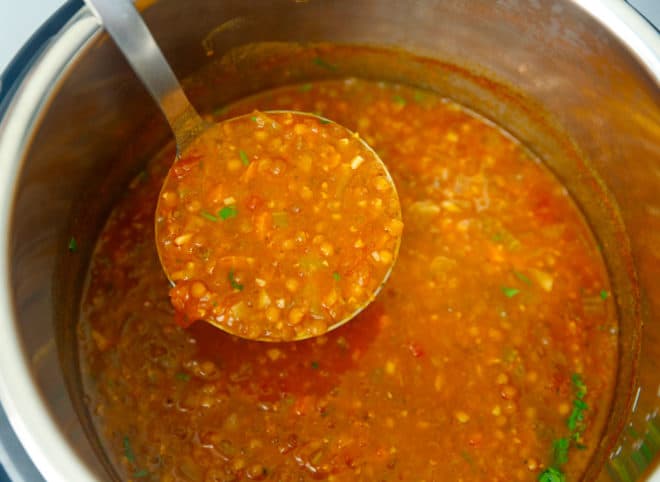A ladle scooping out instant pot lentil soup