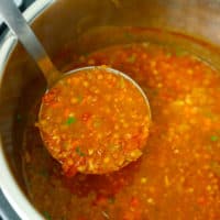 Instant pot filled with lentil soup and a ladle scooping it out