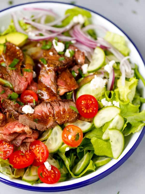 A bowl with mixed greens and steak