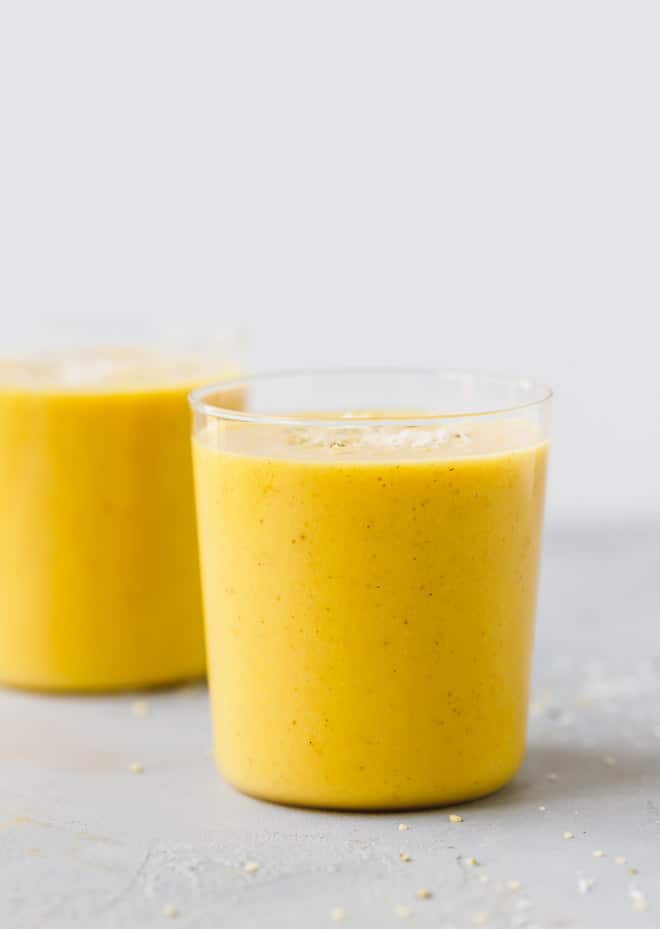 two glasses filled with creamy vegan mango smoothie