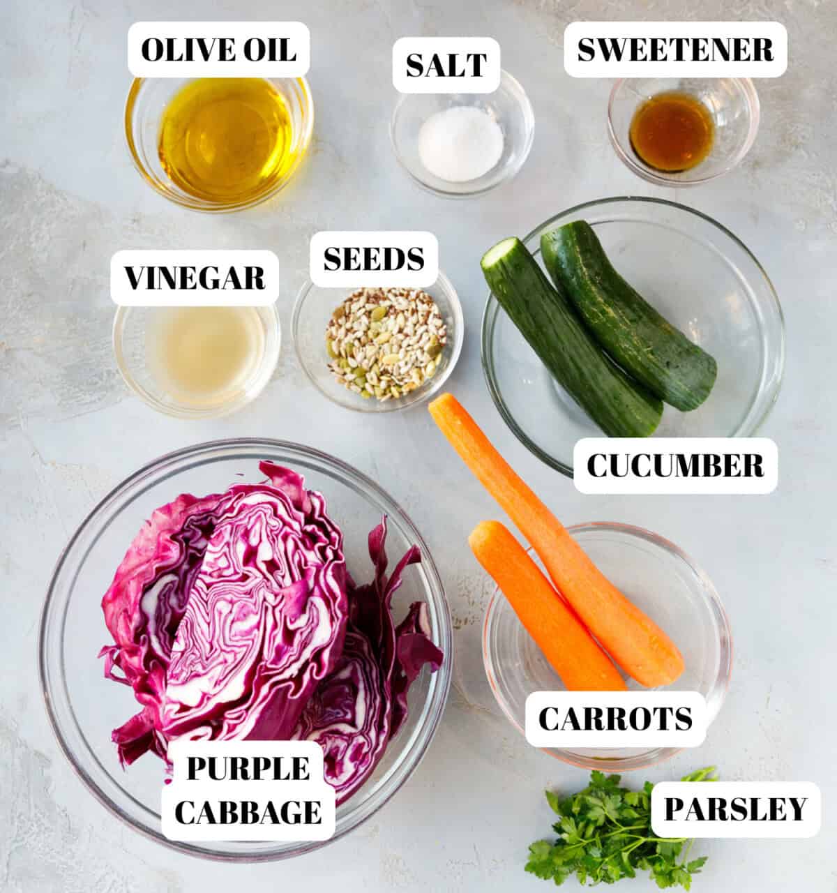 ngredients for purple cabbage salad including red cabbage, cucumbers, carrots, mixed seeds, olive oil, vinegar, salt, sweetener and parsley