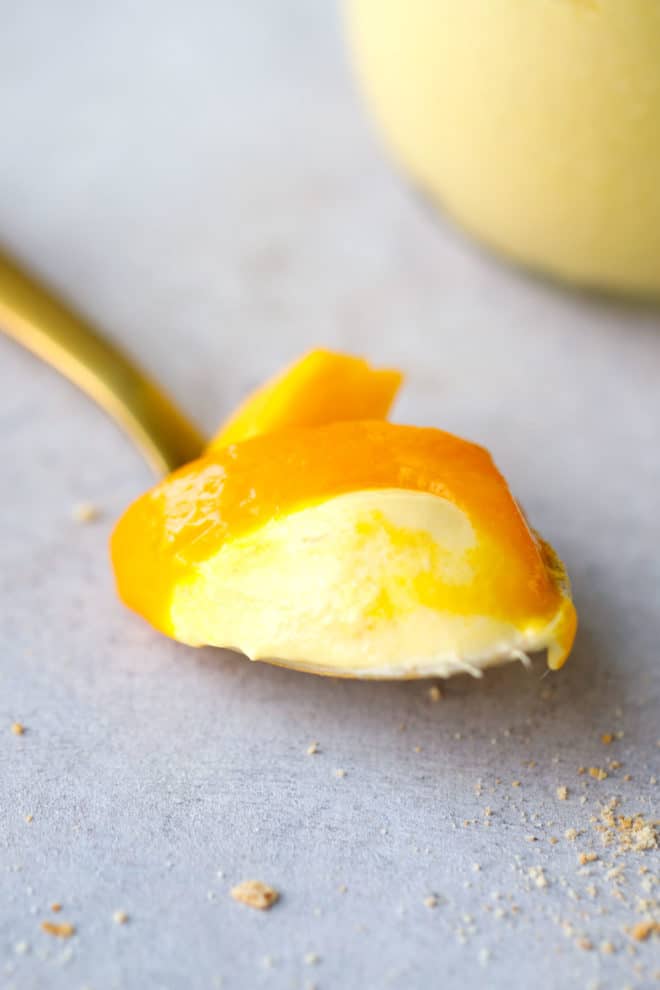 A spoon with mango cheesecake mousse