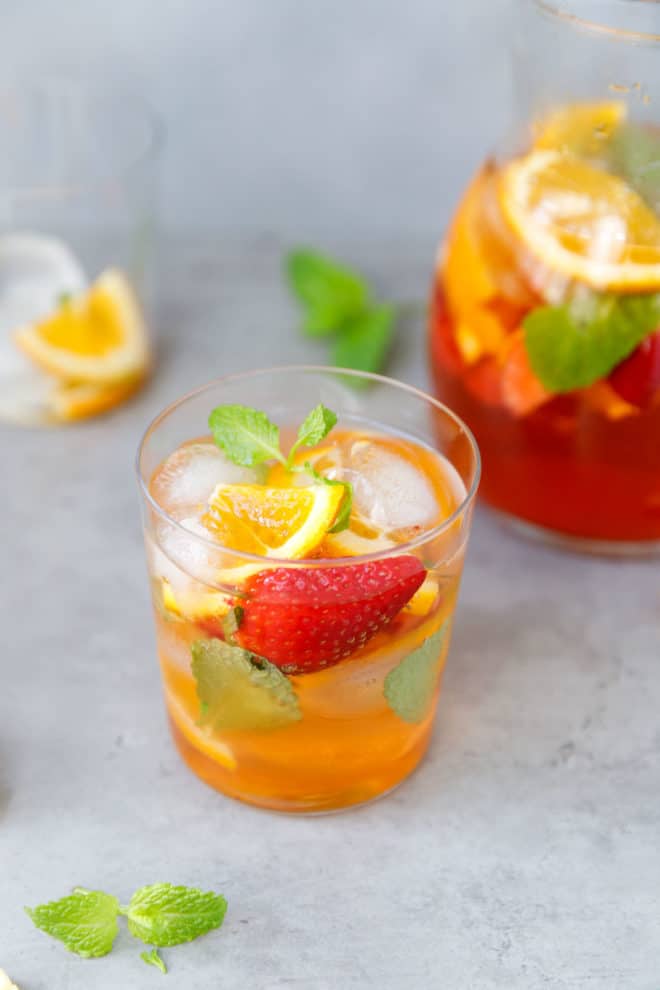 A clear glass with orange, strawberry and rose sangria