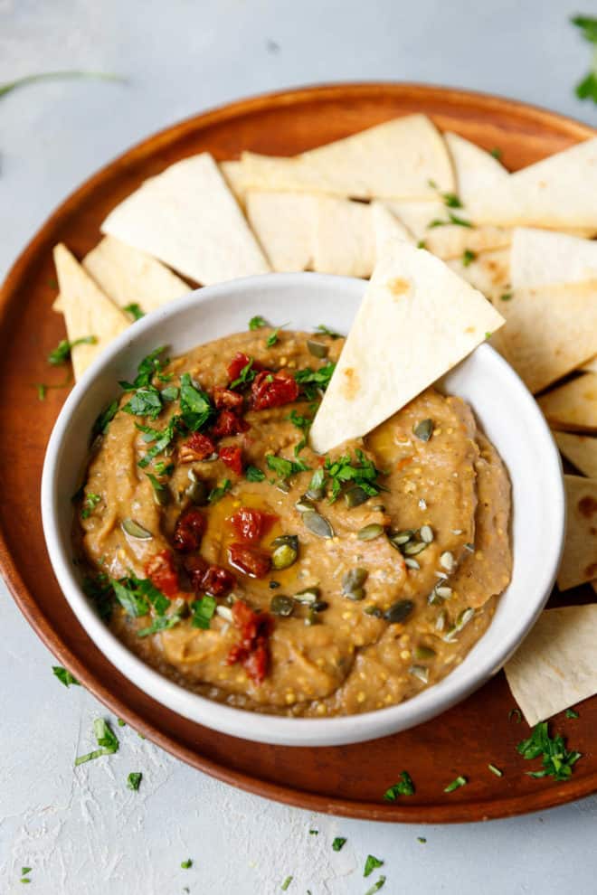 A platter with roasted eggplant dip and pita chips